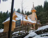 Drewniany kościółek, najwyżej położony kościół w Tatrach, otoczony ośnieżonym lasem.