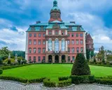 Różowy pałac z wieżą i ogrodem, jeden z wielu pięknych zamków i pałaców Kotliny Kłodzkiej.